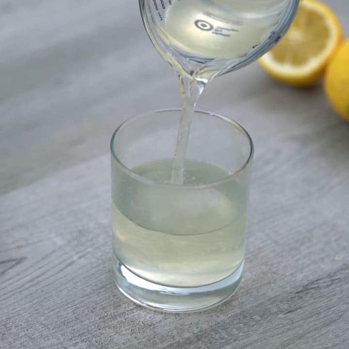 pouring lemon ginger tea in serving glass