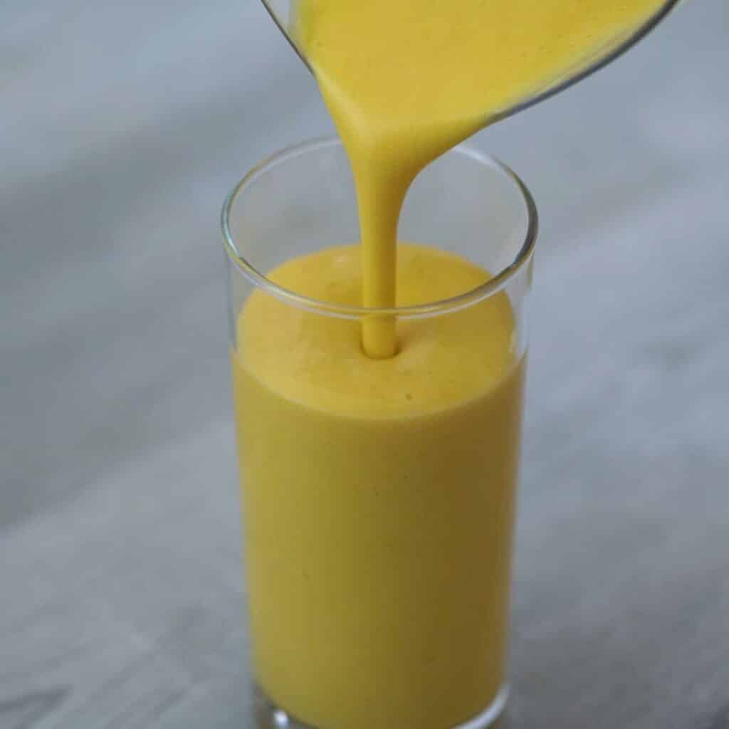 pouring mango lassi to the serving glass