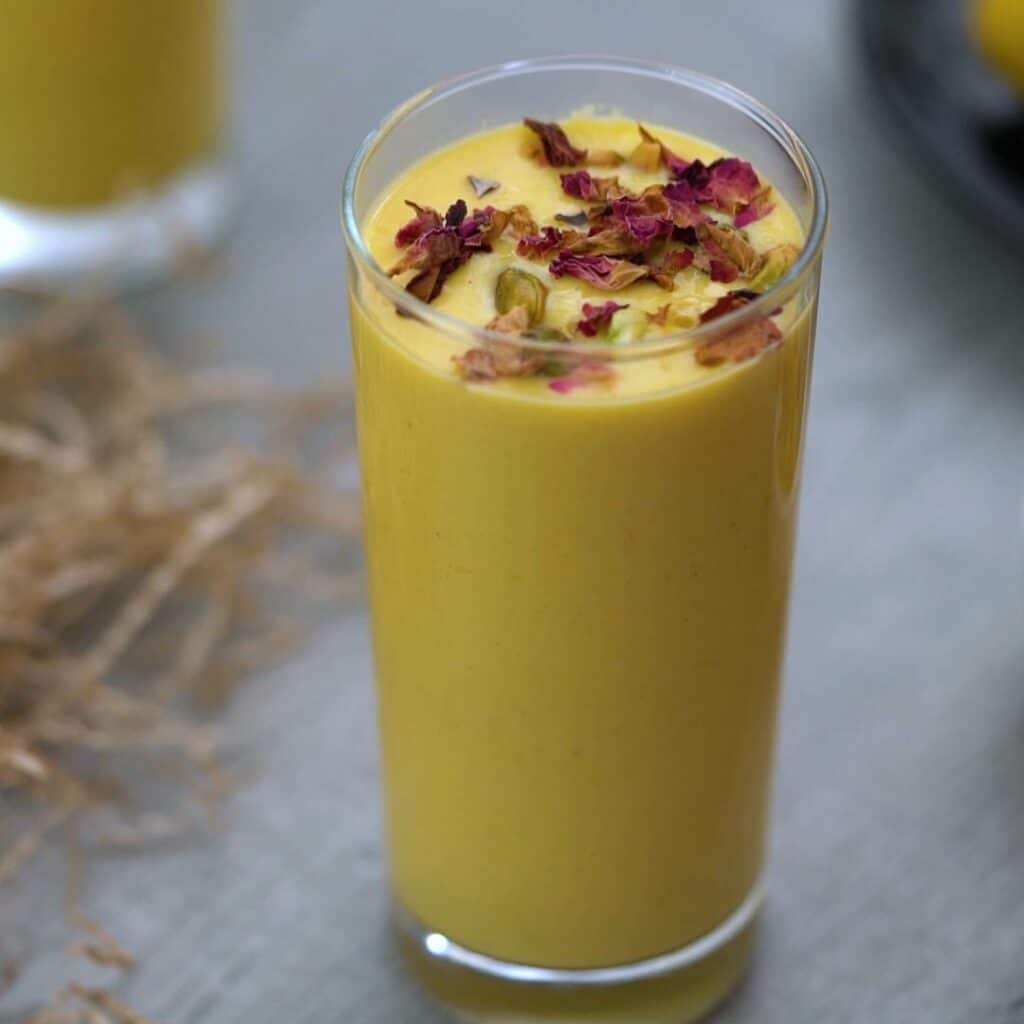 mango lassi garnished with pistachio and rose petals