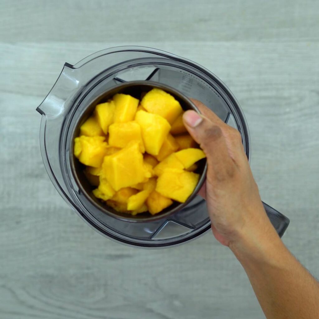 adding mango pulp to blender
