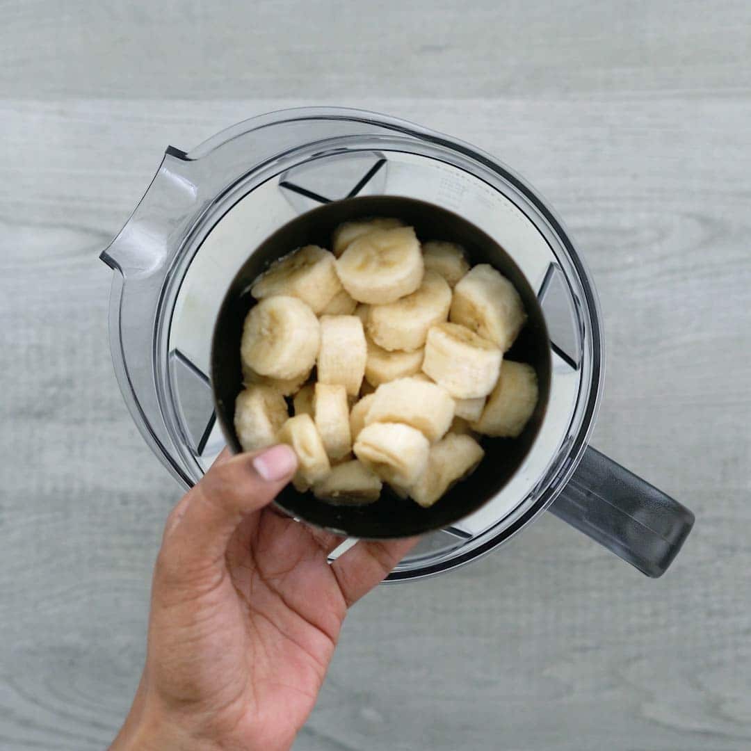 adding banana and other ingredients to the blender