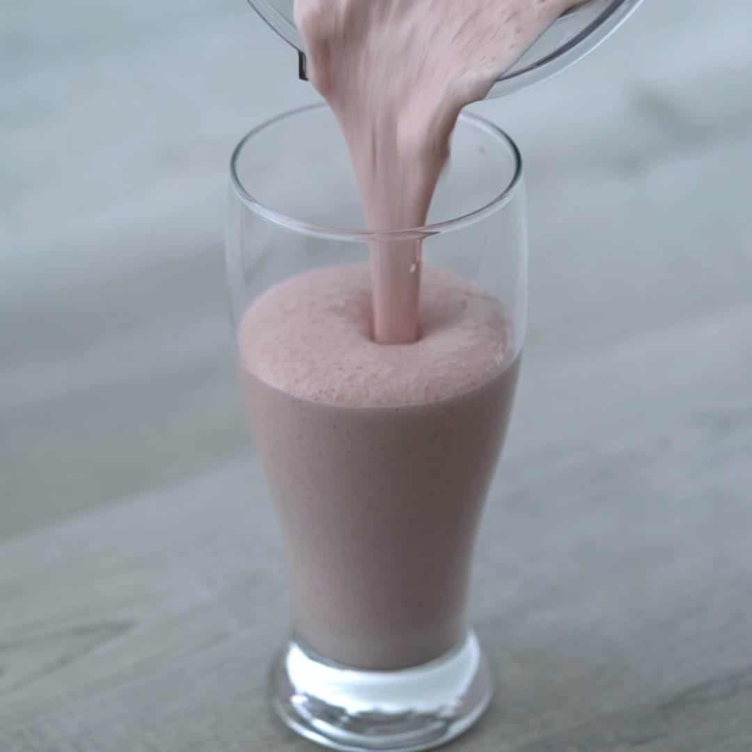 Pouring strawberry milkshake into glass