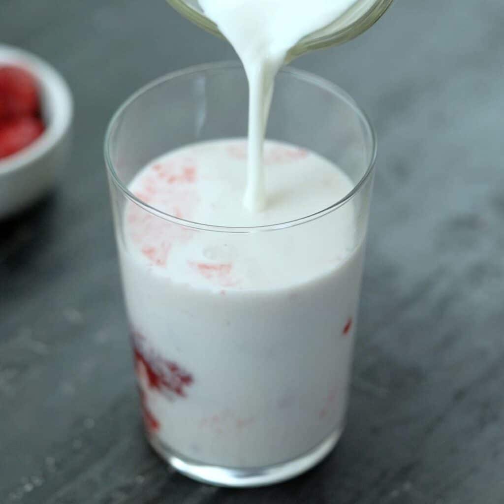 pour cold milk into strawberry syrup