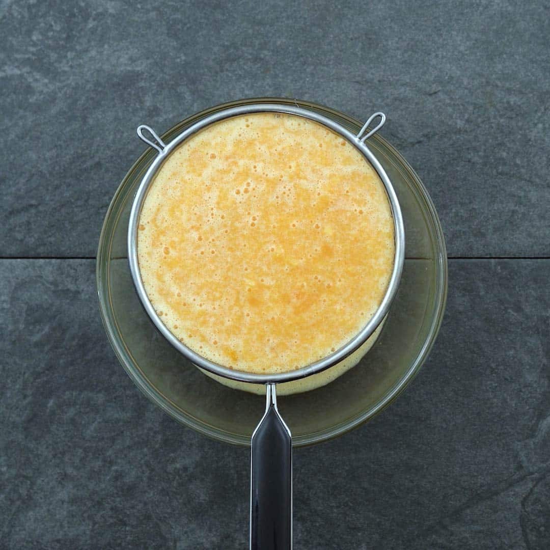filtering orange juice with strainer
