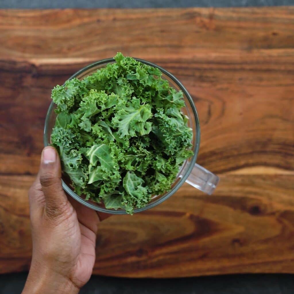 adding kale leaves to blender jar