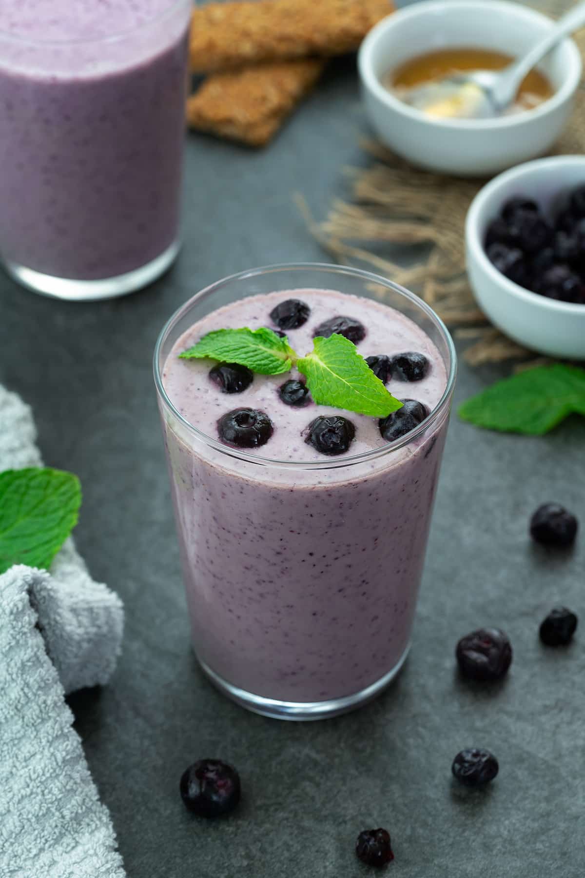 Blueberry Smoothie in a glass placed on a table with few ingredients around