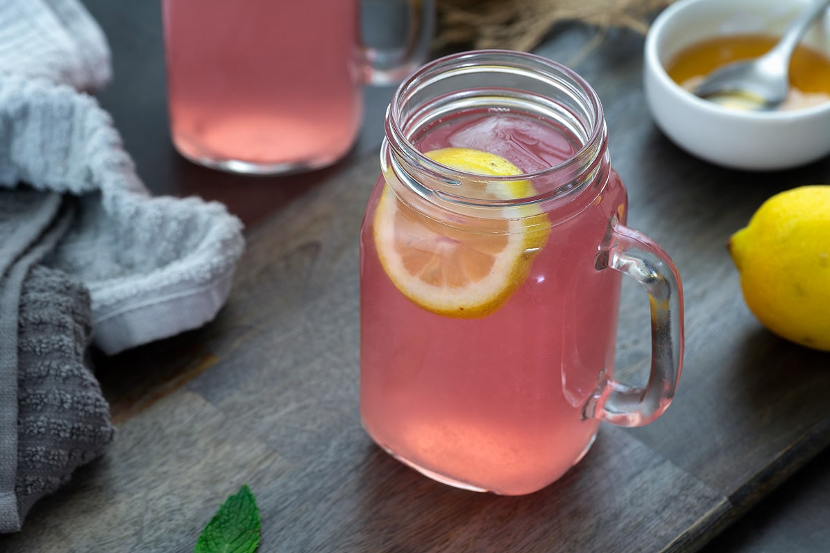 Pink Lemonade in a serving mug. Honey and lemon placed nearby