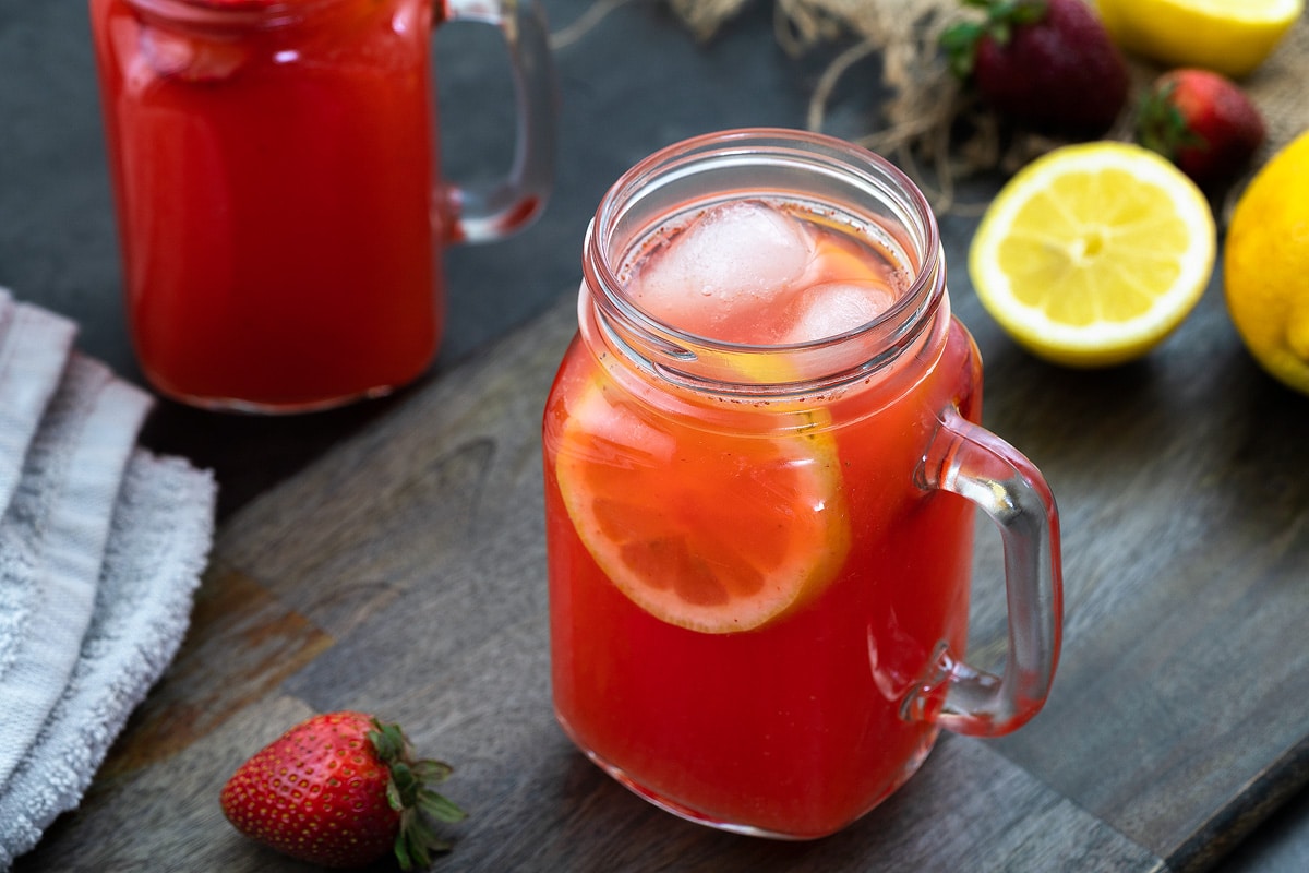 Strawberry Lemonade in a glass mug placed on a table with lemon and strawberry nearby