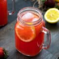 Strawberry Lemonade in a glass mug placed on a table with lemon and strawberry nearby