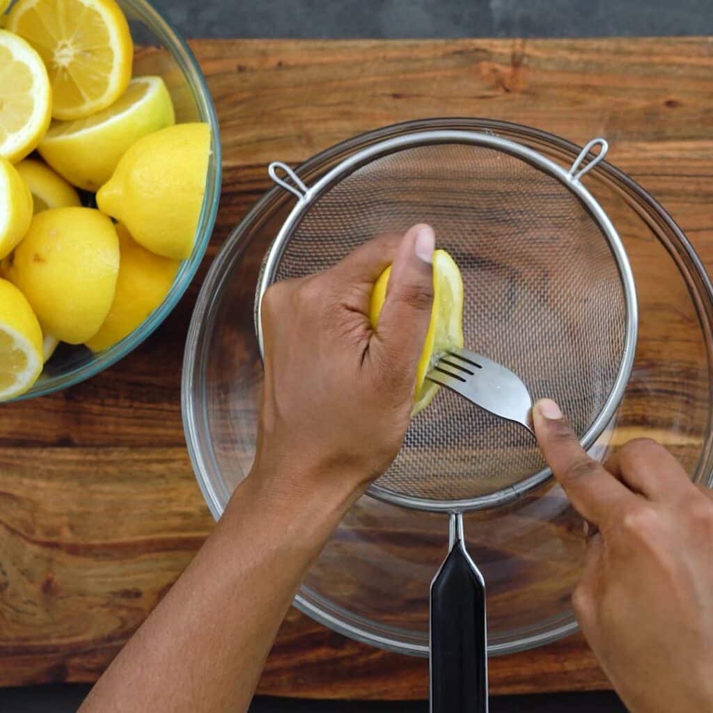 Squeezing the lemon juice over a mesh strainer