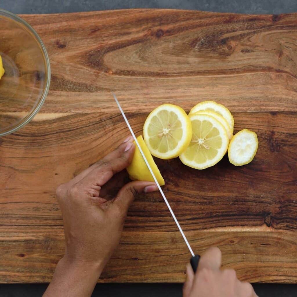 Slicing the lemons with knife on a cutting board