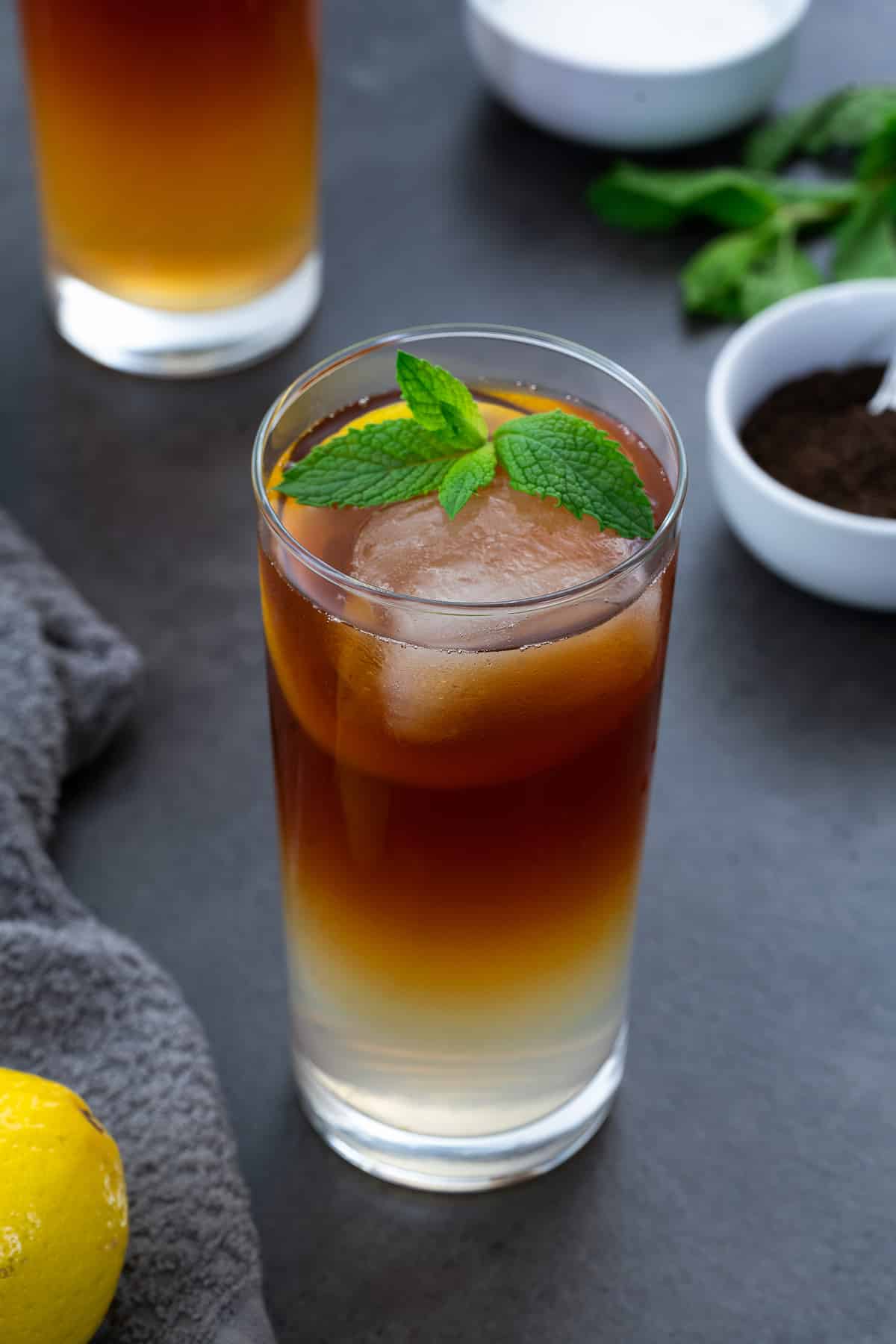 Arnold Palmer drink in a glass placed on a grey table with few ingredients around